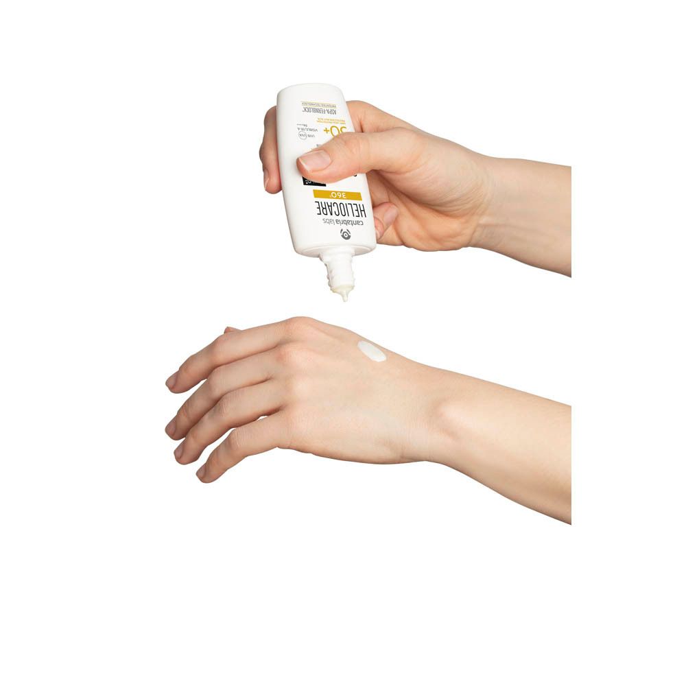 Mains pressant Heliocare 360° Sensation SPF 50+. Crème blanche. Texte : Heliocare, SPF 50+.