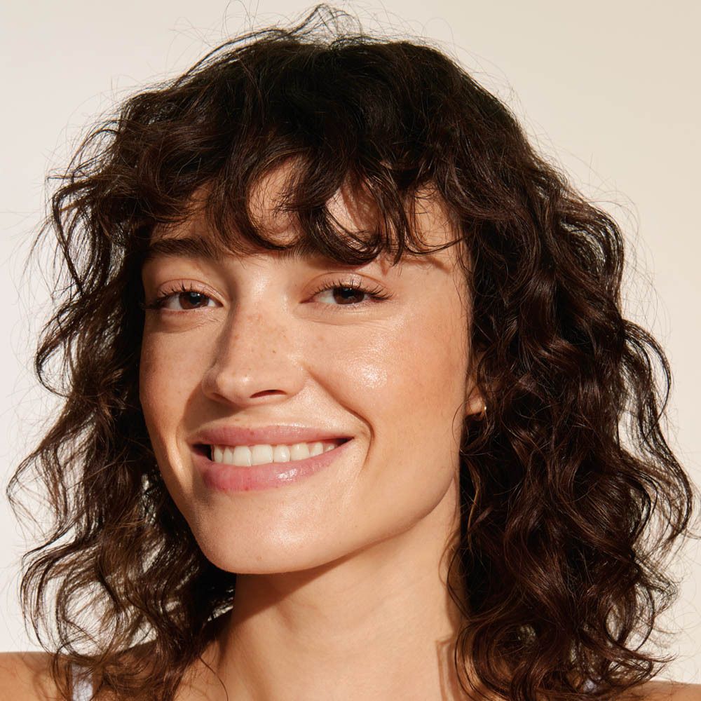 Portret van een vrouw. Ze lacht. Haar huid is glanzend.