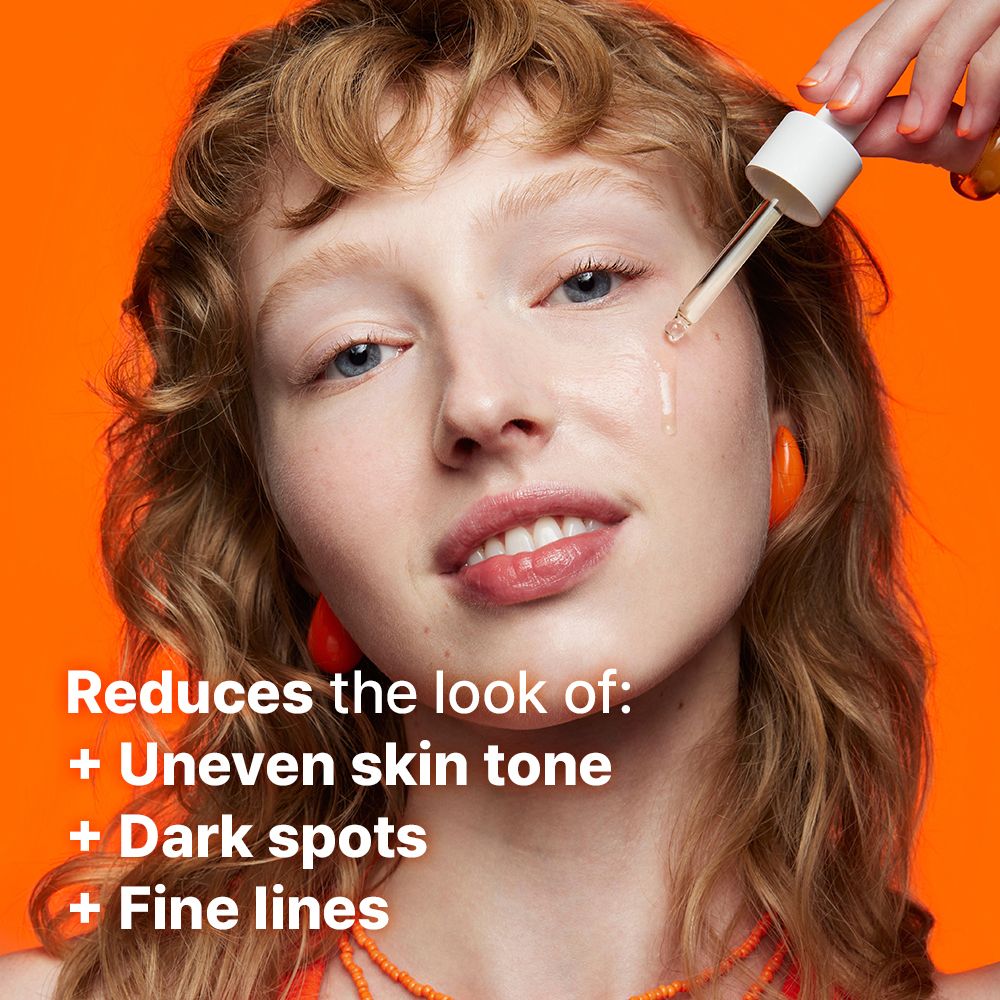 Frau mit Pipette, die Serum auf das Gesicht aufträgt. Text: Reduziert das Aussehen von: ungleichmäßigem Hautton, dunklen Flecken, feinen Linien.