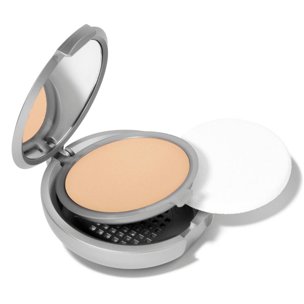 Poudre compacte claire, miroir et applicateur. Boîtier argenté, couvercle ouvert.
