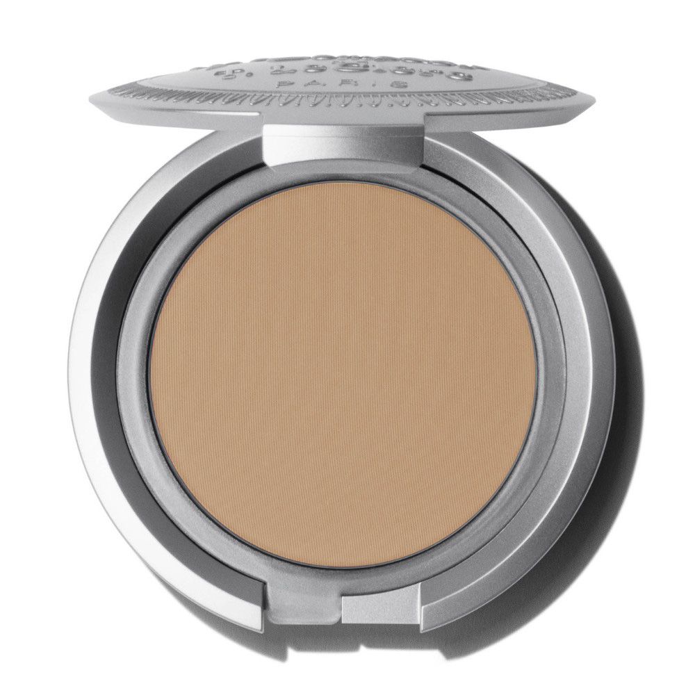 Fond de teint compact. Boîtier rond argenté ouvert. Poudre beige clair. Inscription sur le couvercle.