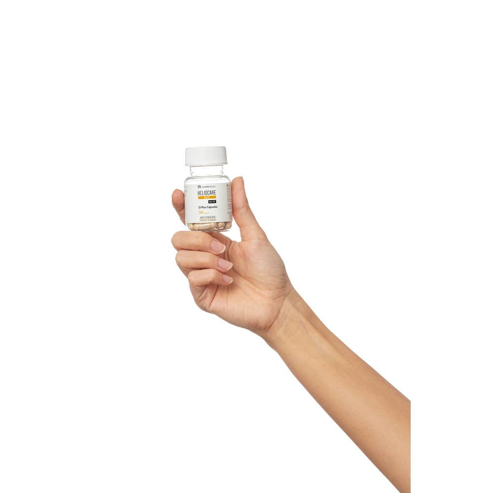 Hand die fles Heliocare 360° D Plus Capsules vasthoudt. Witte achtergrond.