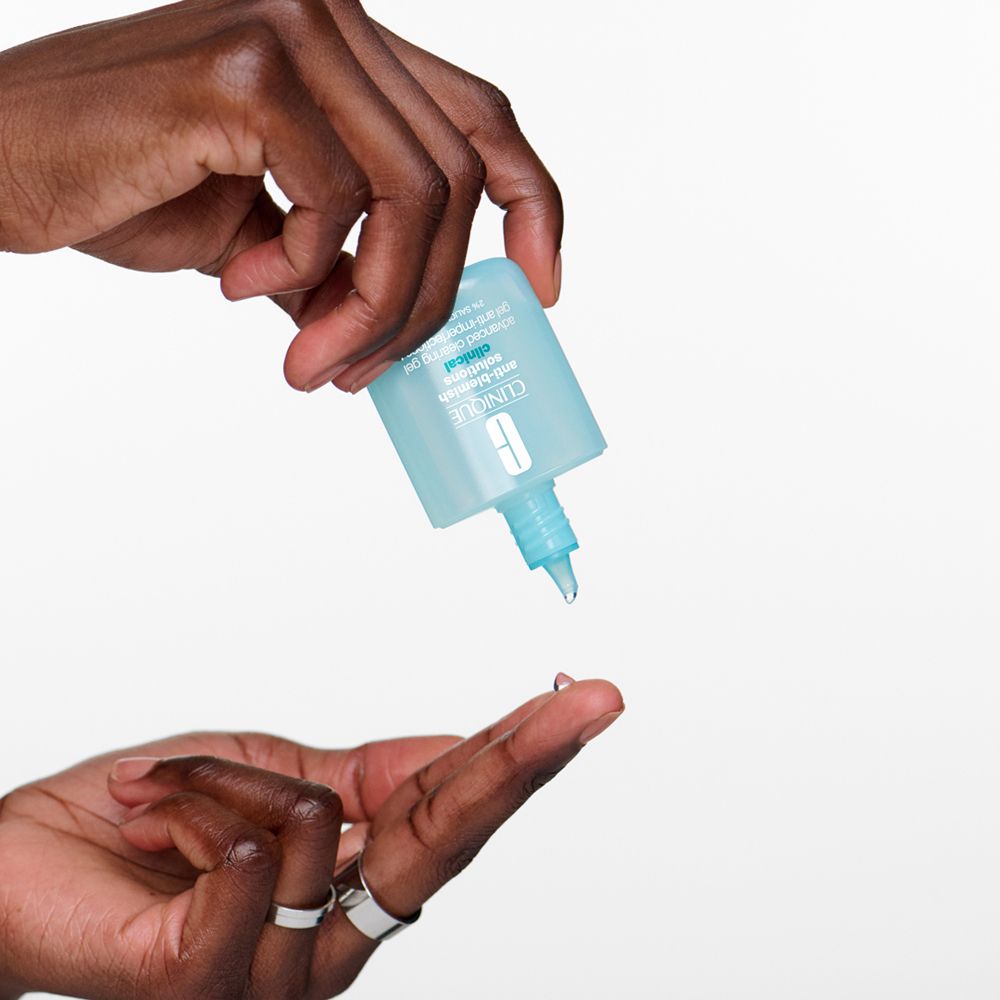 Hände halten ein Fläschchen und tropfen Gel auf einen Finger. Fläschchen ist blau.