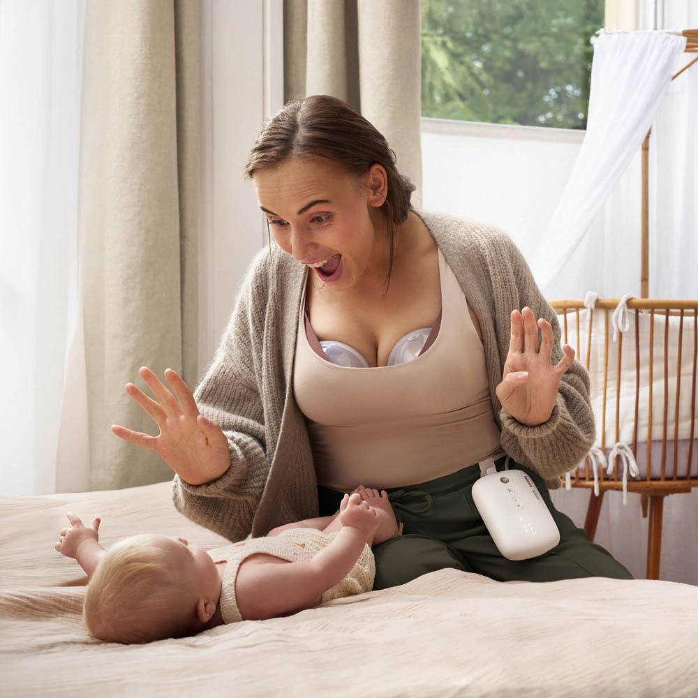 Femme avec tire-lait portable et bébé. La pompe est attachée à la ceinture.