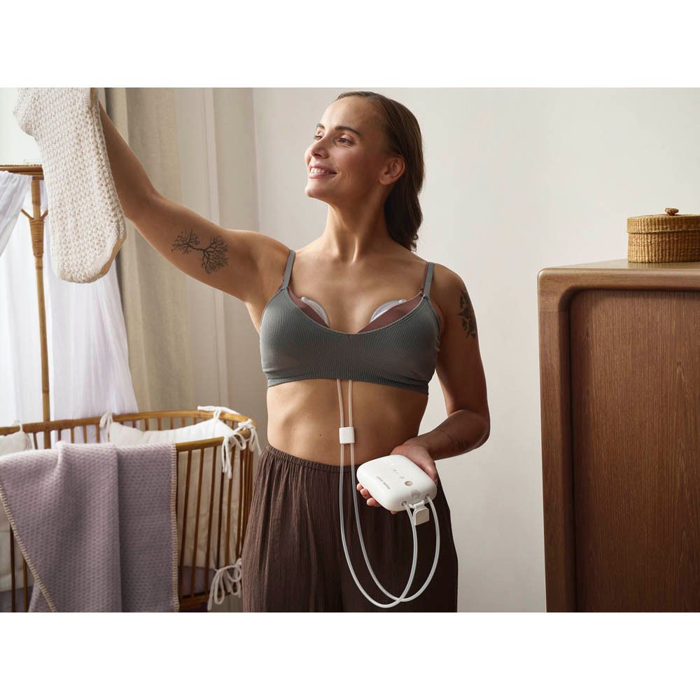 Femme portant un tire-lait et des coussinets mammaires dans un soutien-gorge. Un petit moteur est visible.
