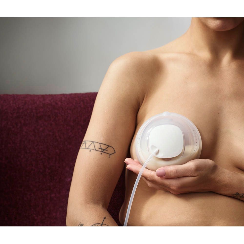 Une femme utilise un tire-lait portable avec un tuyau.