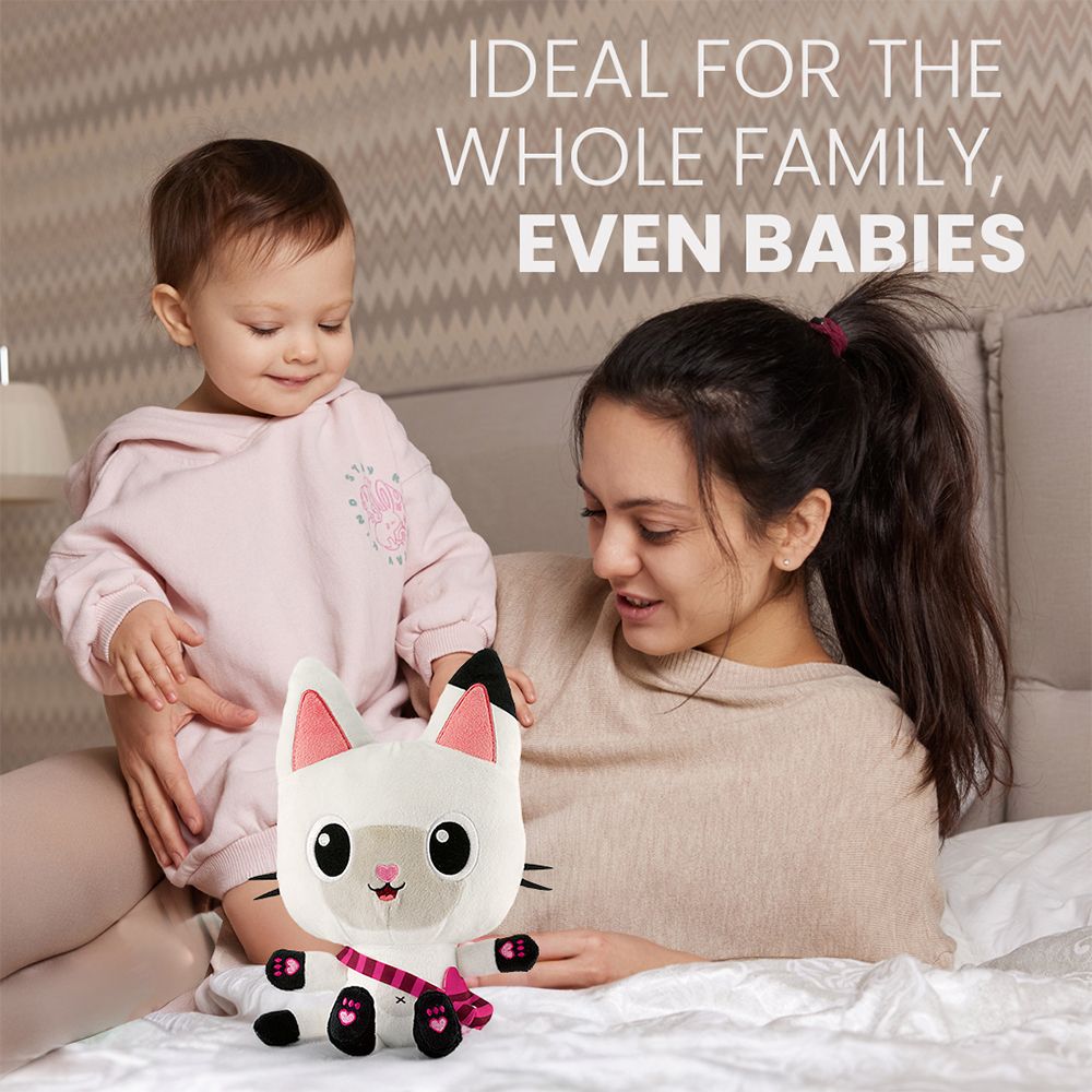 Frau mit Baby hält ein Katzen-Plüschtier auf einem Bett. Text: Ideal für die ganze Familie, auch für Babys.