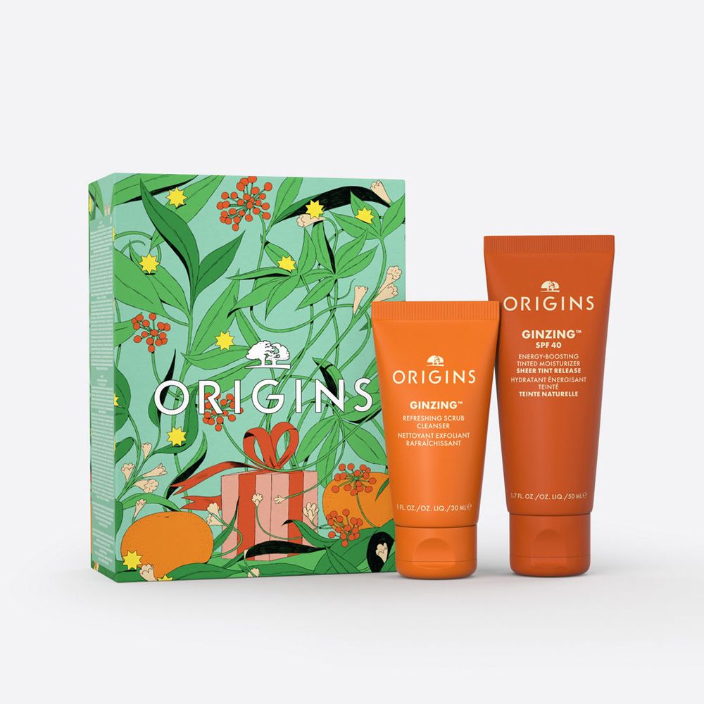 Set mit zwei orangefarbenen Tuben und einer Geschenkbox mit floralem Design. Auf den Tuben steht "GINZING" und "ORIGINS".