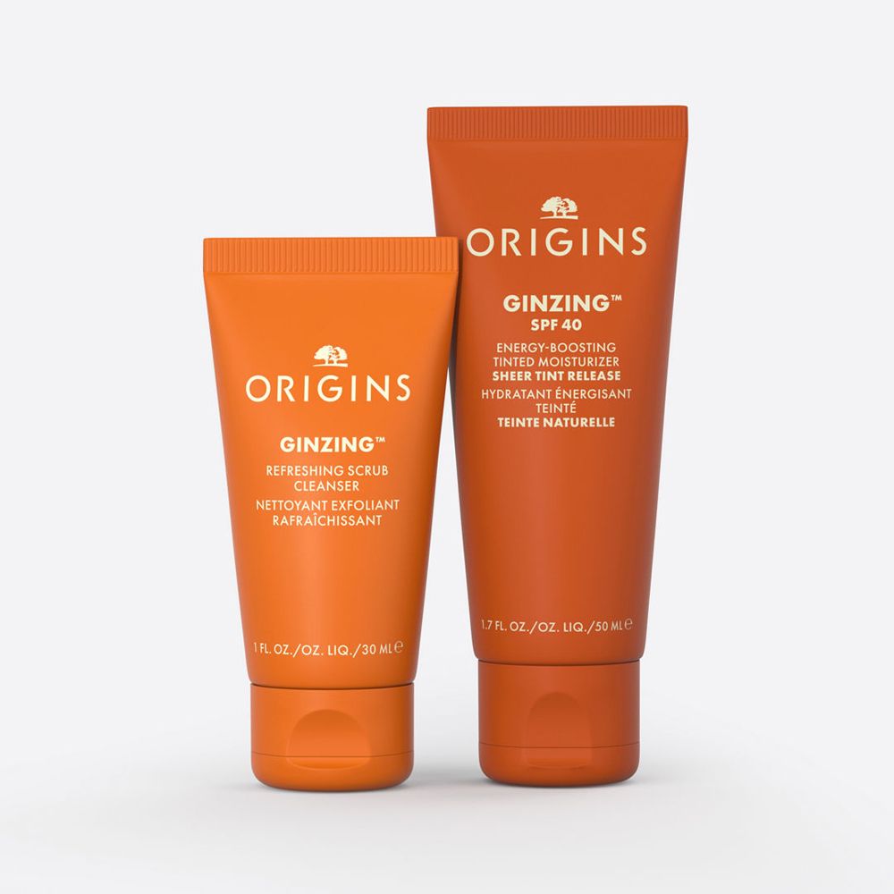 Zwei orangefarbene Tuben mit den Aufschriften "ORIGINS" und "GINZING". Eine Tube ist kleiner als die andere.