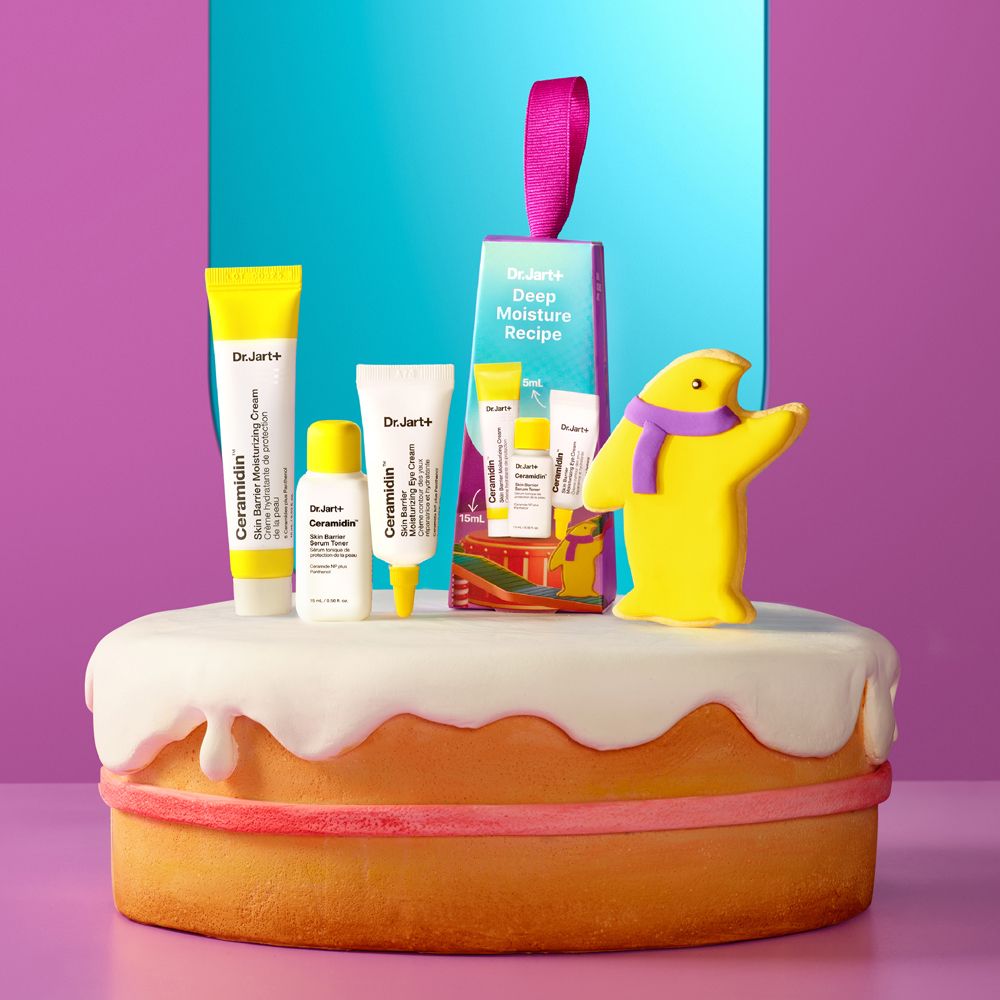 Geschenkset mit Hautpflegeprodukten auf einem Kuchen. Enthält Cremes und eine Verpackung mit lila Schleife. Aufschrift: Dr. Jart+ Deep Moisture Recipe.