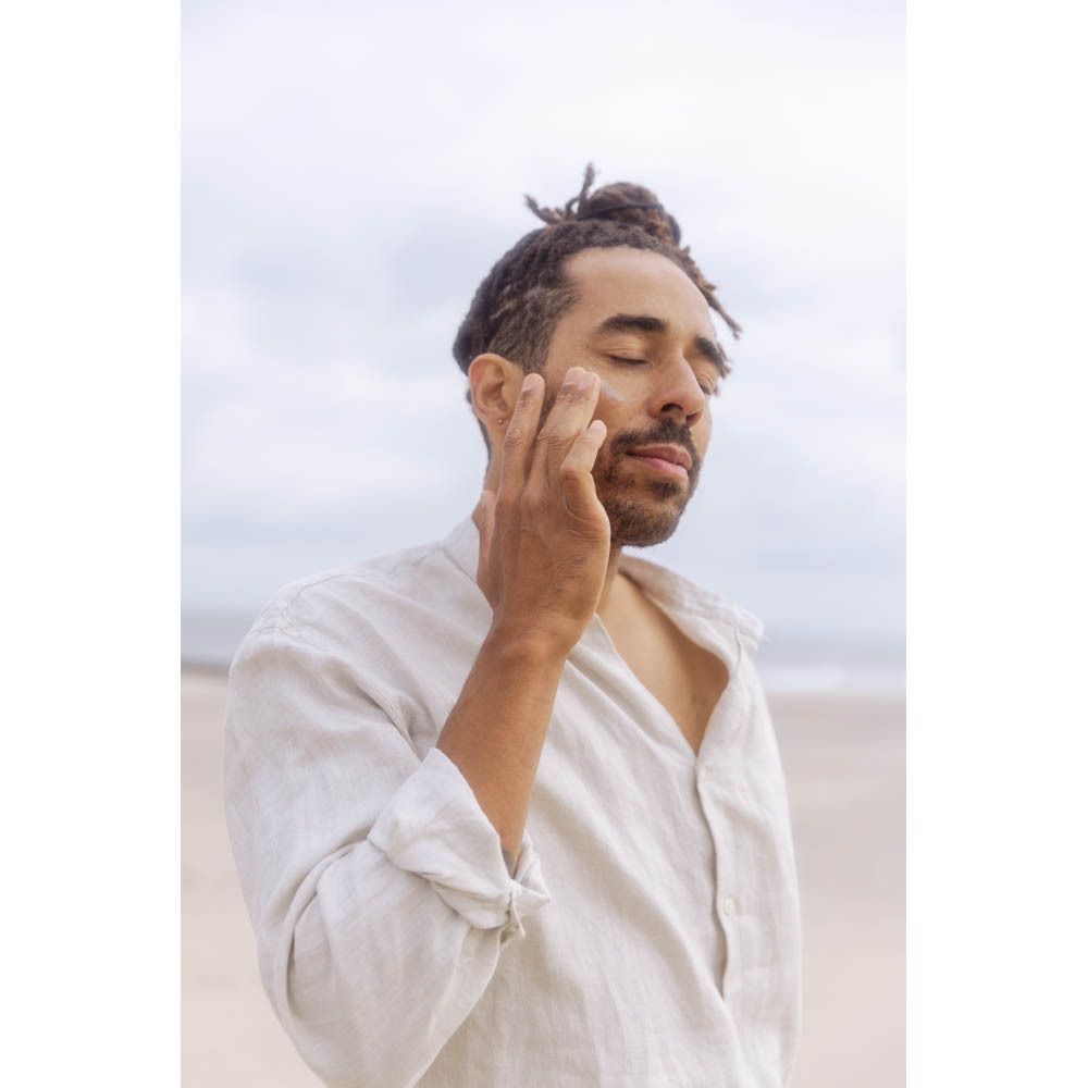Un homme avec une fleur devant le visage. Aucun produit visible.