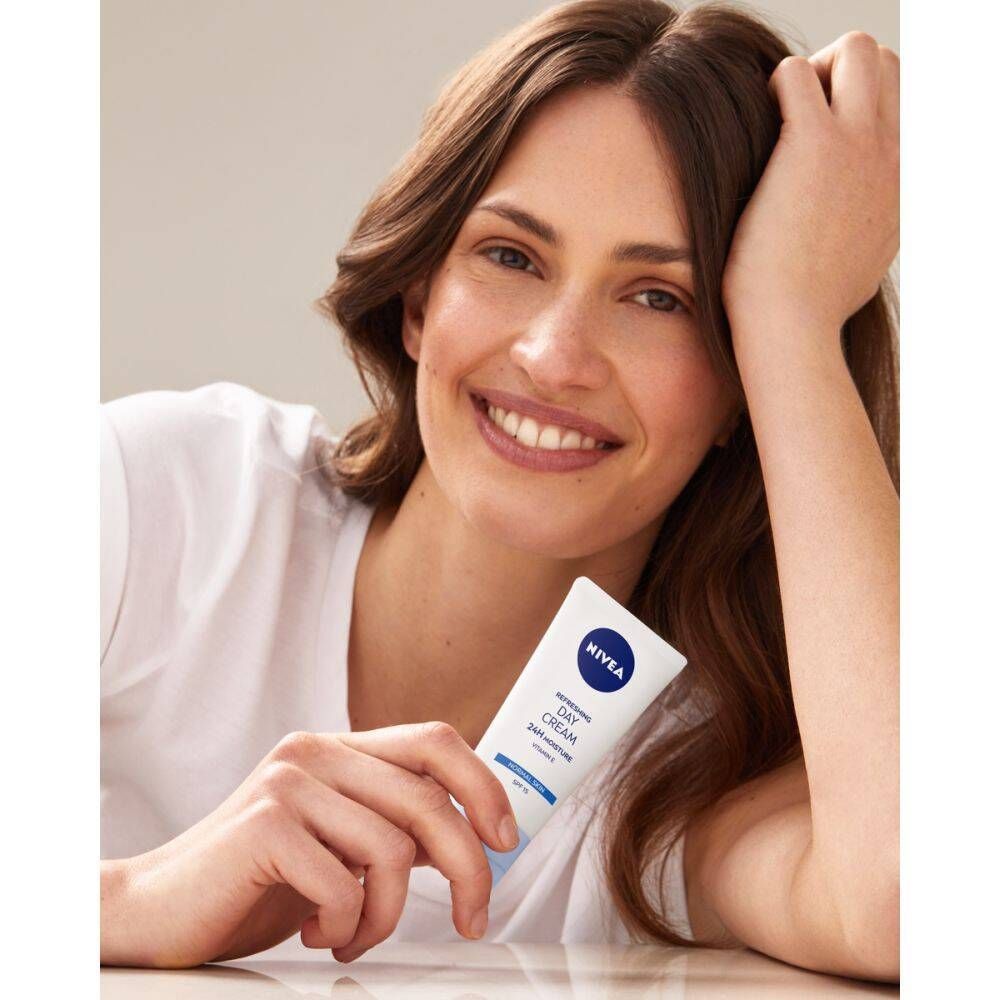 Femme tenant un tube blanc avec bouchon bleu. Logo NIVEA et texte : Daily Essentials, Light Moisturising Day Cream SPF 15.