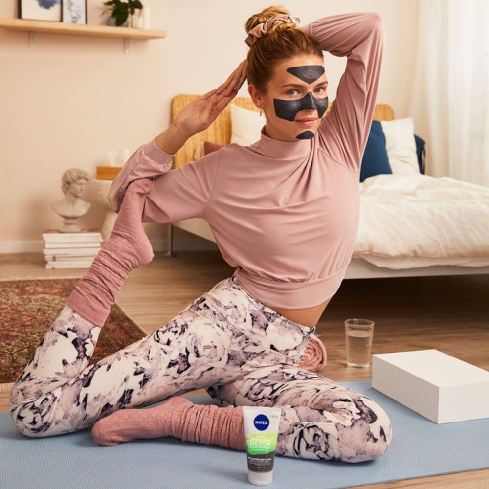 Femme en posture de yoga avec masque facial et produit NIVEA. Un tube NIVEA Urban Skin Detox Mask est au sol.