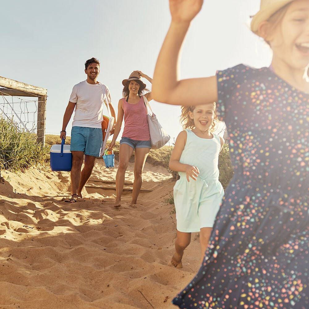 Famille sur la plage. Une femme fait signe. Sable, mer, ciel bleu.