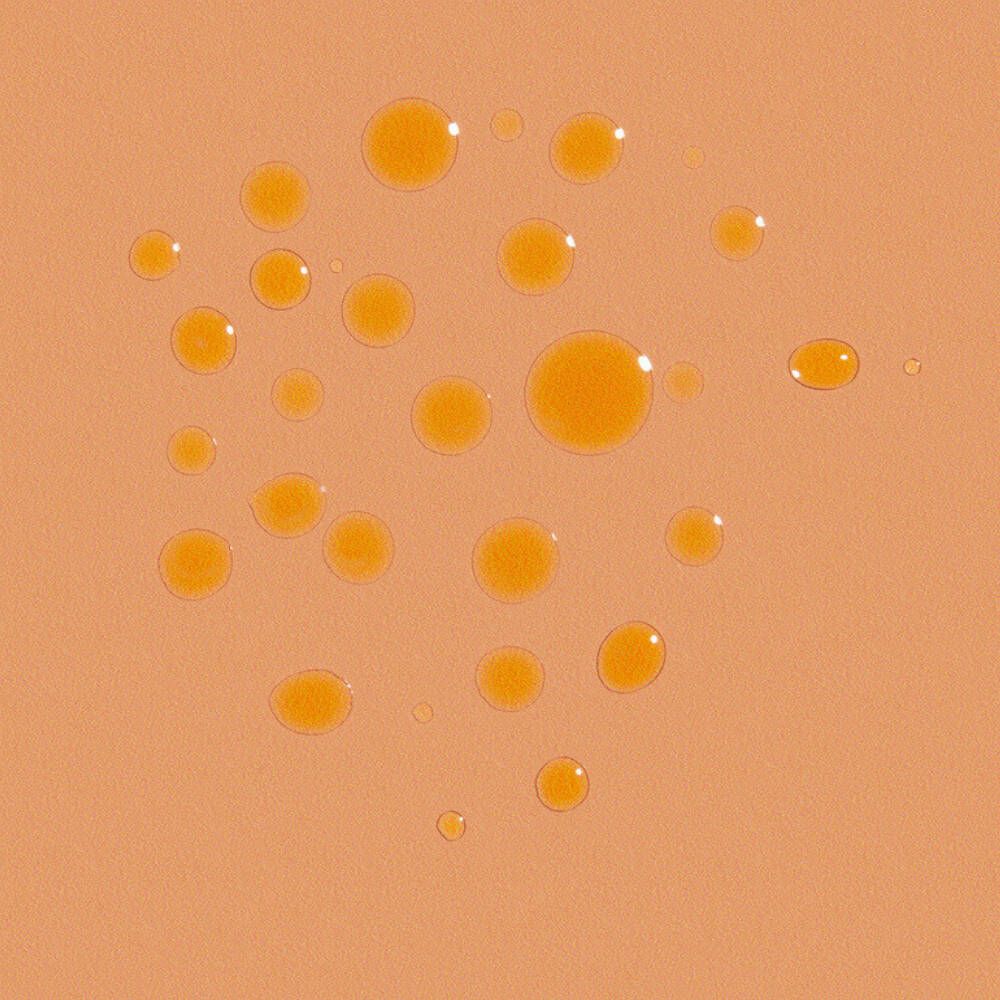 Gros plan de gouttes d'huile solaire sur fond orange. Les gouttes sont rondes et de tailles différentes.
