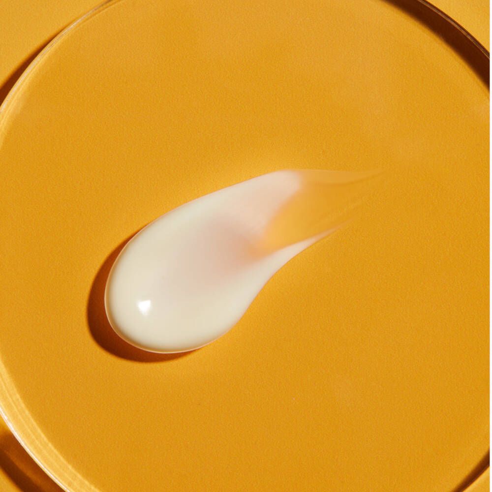 Klecks Sonnencreme auf gelbem Hintergrund. Creme-Textur, weiß. Geformt wie ein Tropfen.
