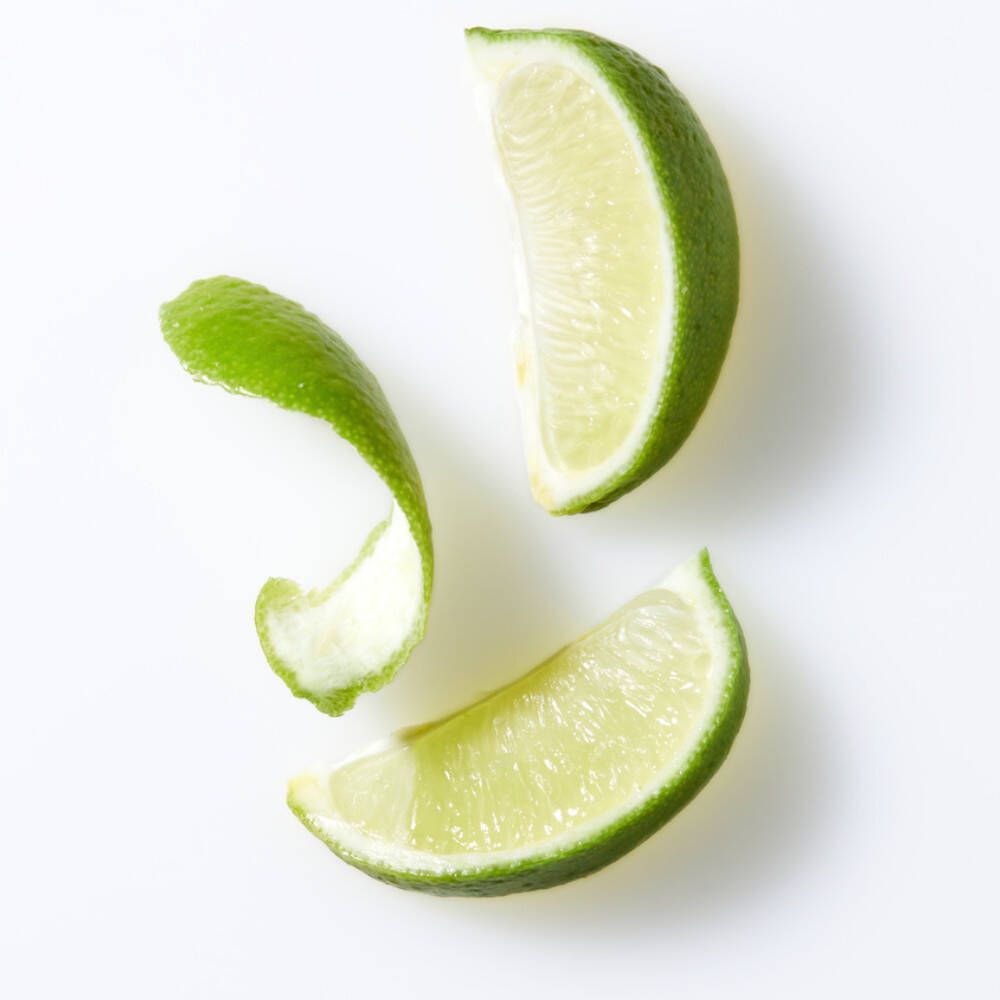 Drie limoenschijfjes en een schil op witte achtergrond.
