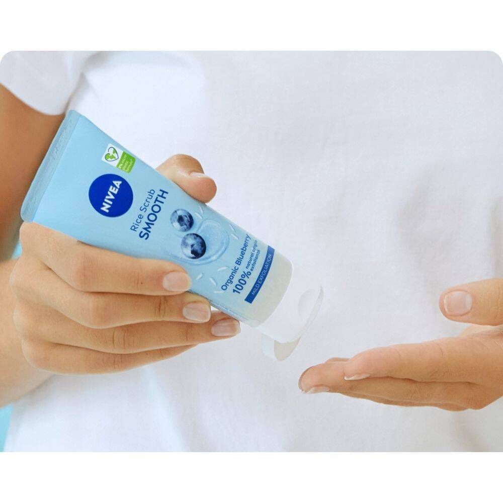 Personne tenant un tube bleu clair avec logo NIVEA et texte. Produit pressé dans la paume.
