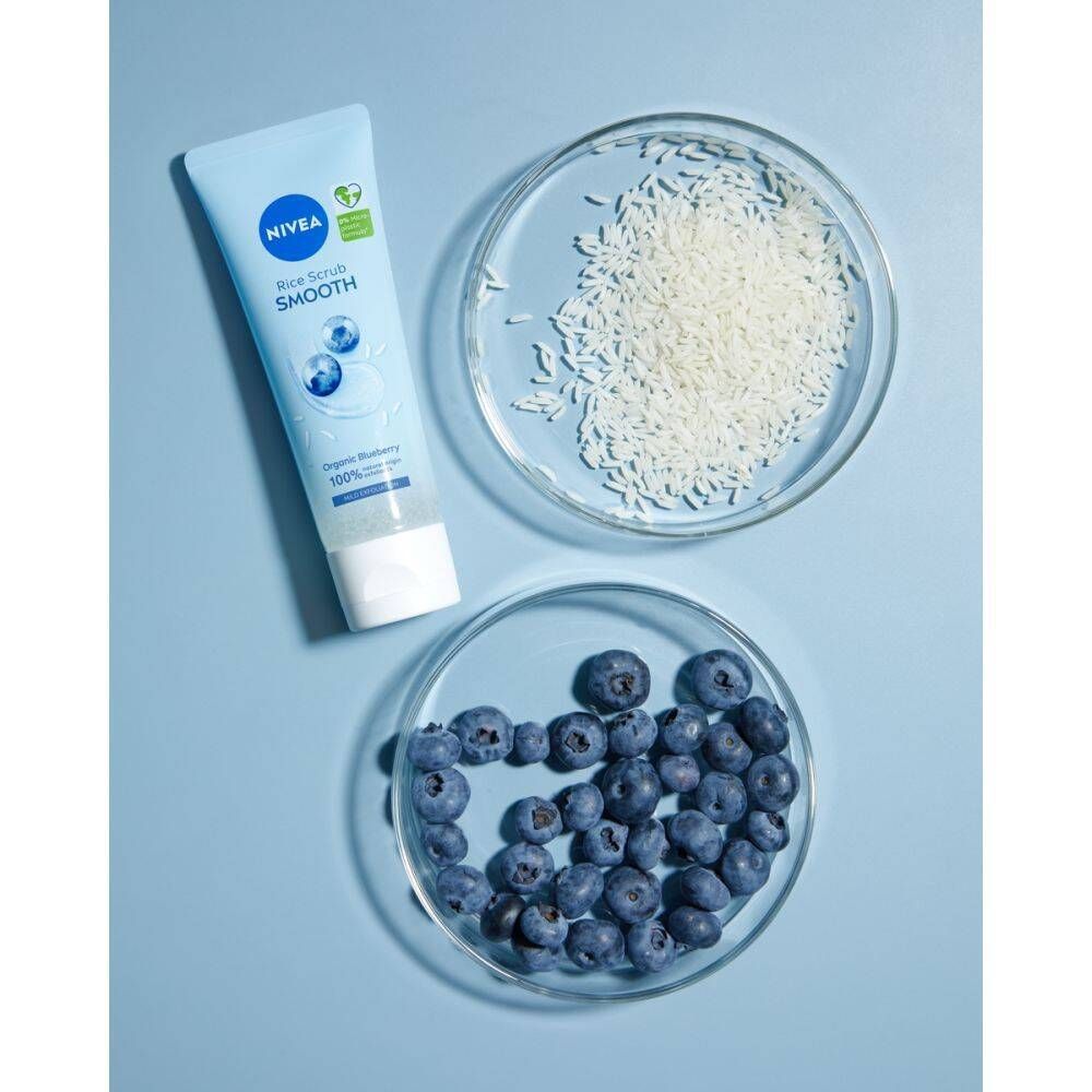 Tube bleu clair, à côté de deux bols en verre avec du riz et des myrtilles. Fond bleu.