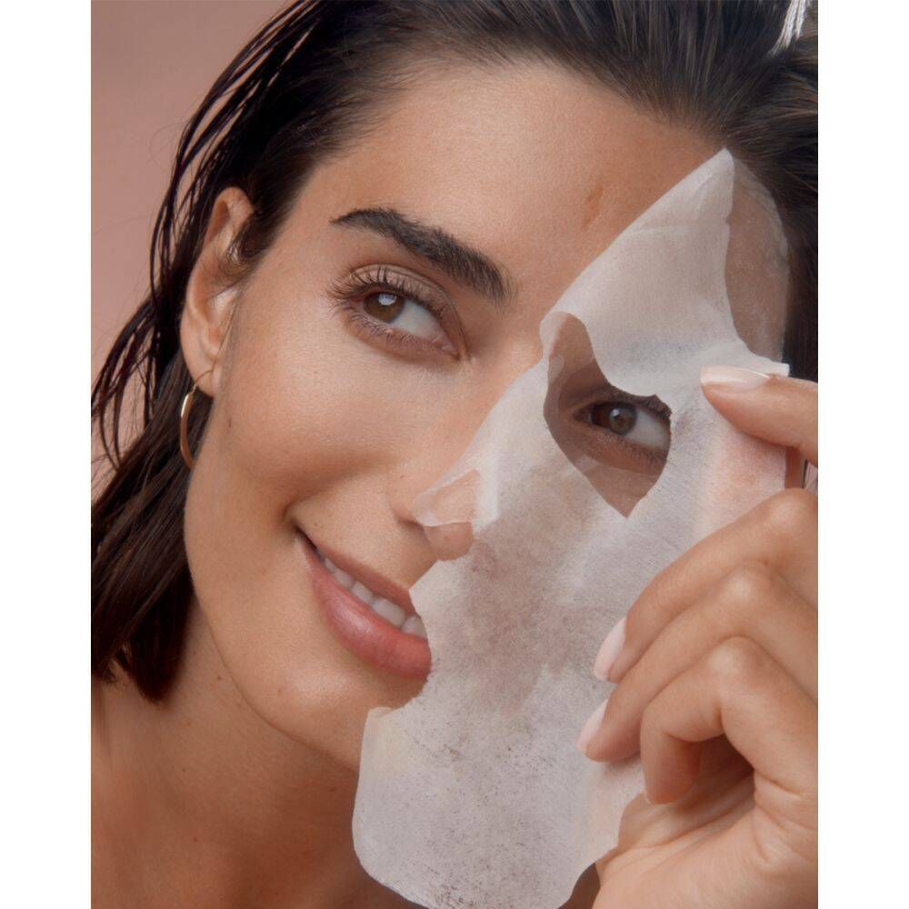 Vrouw houdt een gezichtsmasker voor haar gezicht. Het masker bedekt de helft van het gezicht. Huidverzorgingsproduct.