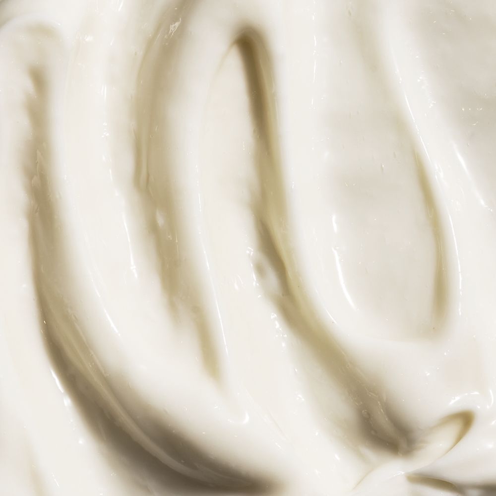 Gros plan de crème. Texture lisse, couleur crème avec lignes ondulées.