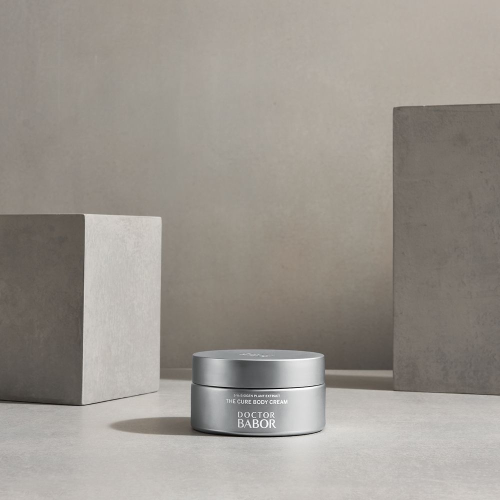 Pot argenté sur table. Inscription : THE CURE BODY CREAM, DOCTOR BABOR.