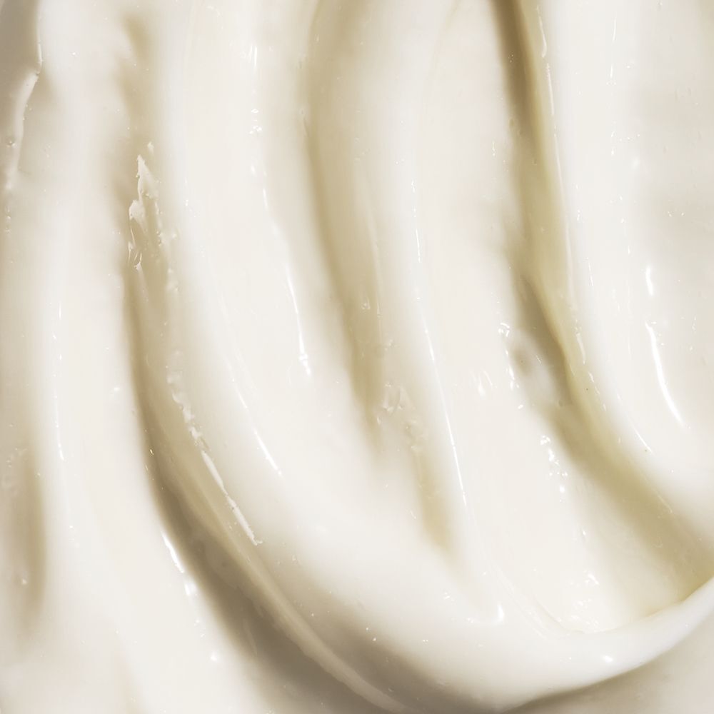 Gros plan de crème. Texture lisse, couleur crème avec lignes ondulées.