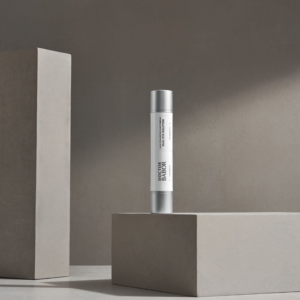 Produkt auf einem grauen Podest. Doctor BABOR Dual Eye Solution, zylindrische Flasche.