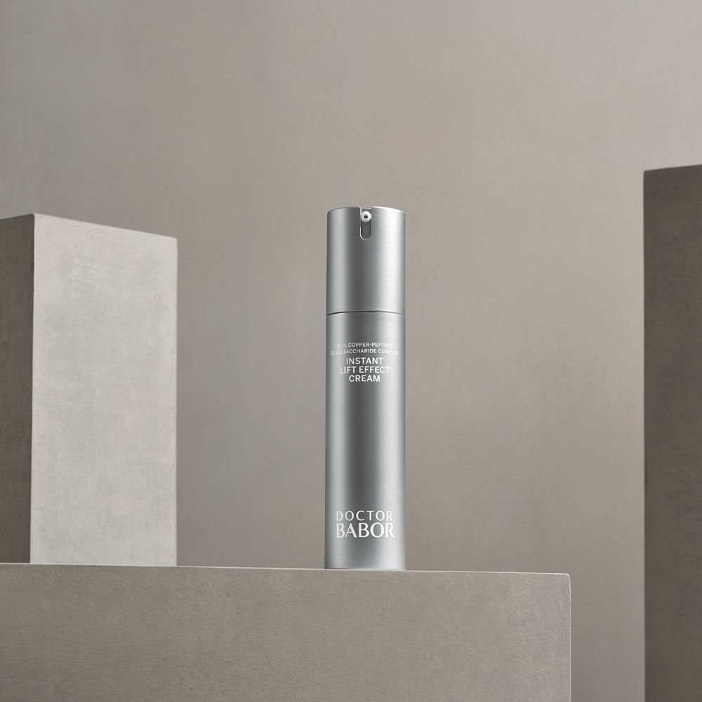 Silberne Creme-Tube auf einer grauen Oberfläche. Beschriftung: Instant Lift Effect Cream, Doctor BABOR.