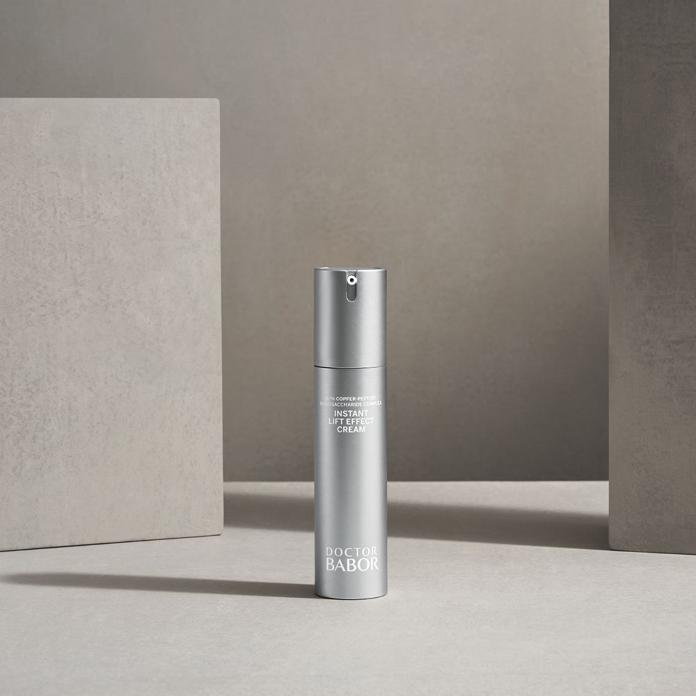 Silberne Creme-Tube auf einer grauen Oberfläche. Beschriftung: Instant Lift Effect Cream, Doctor BABOR.