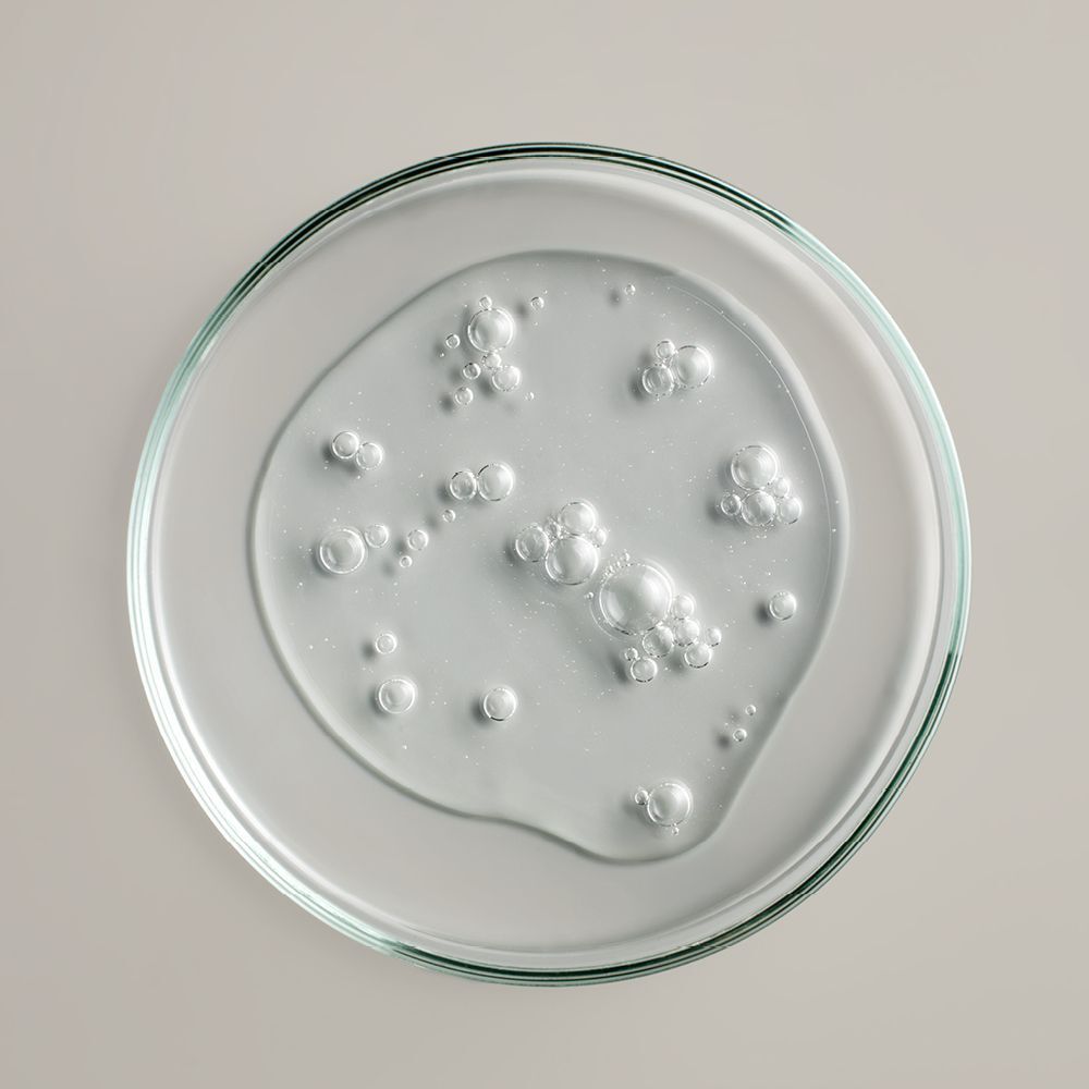 Klare Flüssigkeit auf einer Glasschale. Blasen sichtbar.