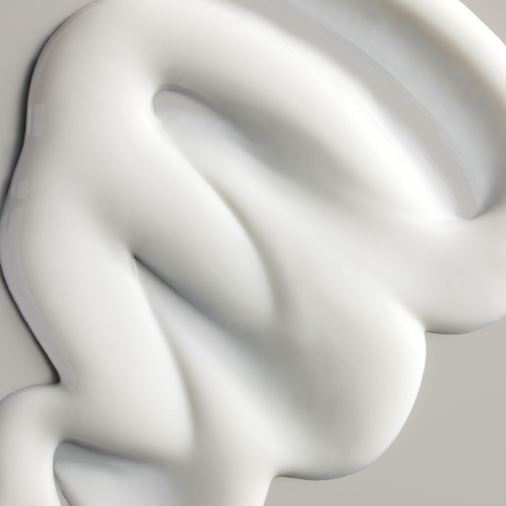Nahaufnahme einer weißen Creme. Die Creme ist gewellt und hat eine glatte Textur.