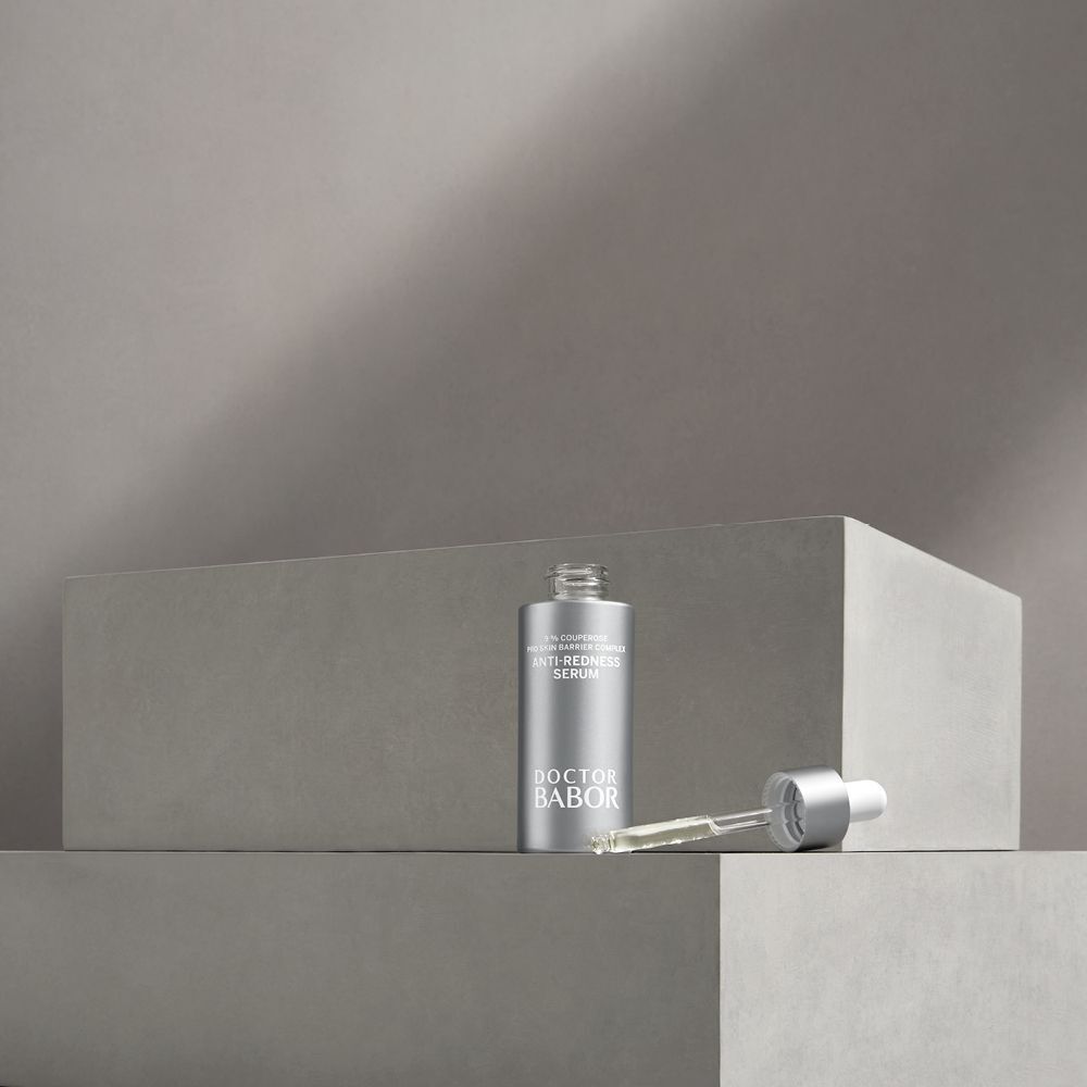 Serum-Flasche und Applikator auf grauen Blöcken. Aufschrift: Anti-Redness Serum, Doctor BABOR.