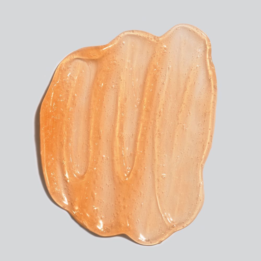 Gros plan d'un baume orange sur fond gris. Texture visible.