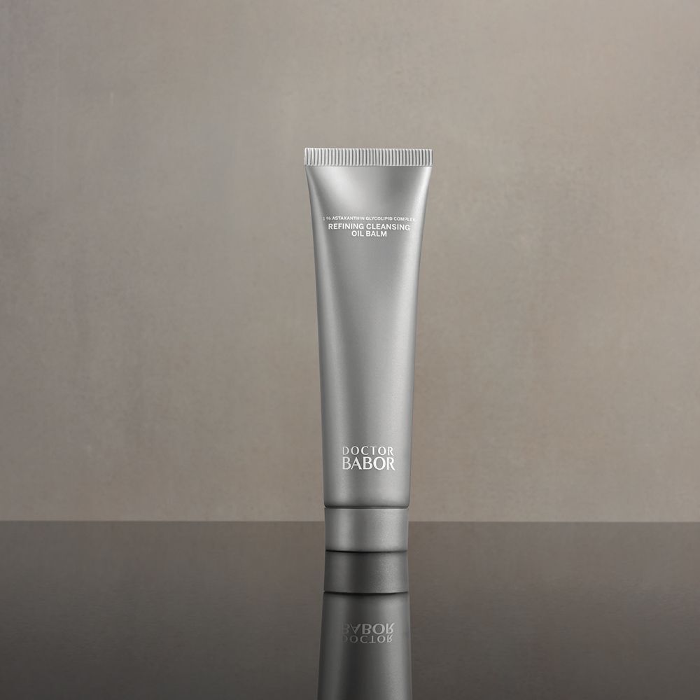 Tube argenté sur surface brillante. Inscription: Refining Cleansing Oil Balm. Marque: Doctor BABOR.