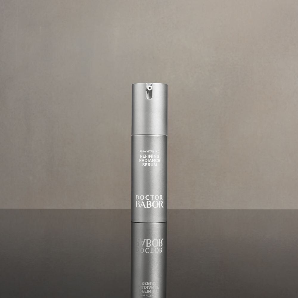 Silberne Serumflasche mit Sprühkopf. Beschriftung: 10% Vitamin C, Refining Radiance Serum, Doctor BABOR. Spiegelung.