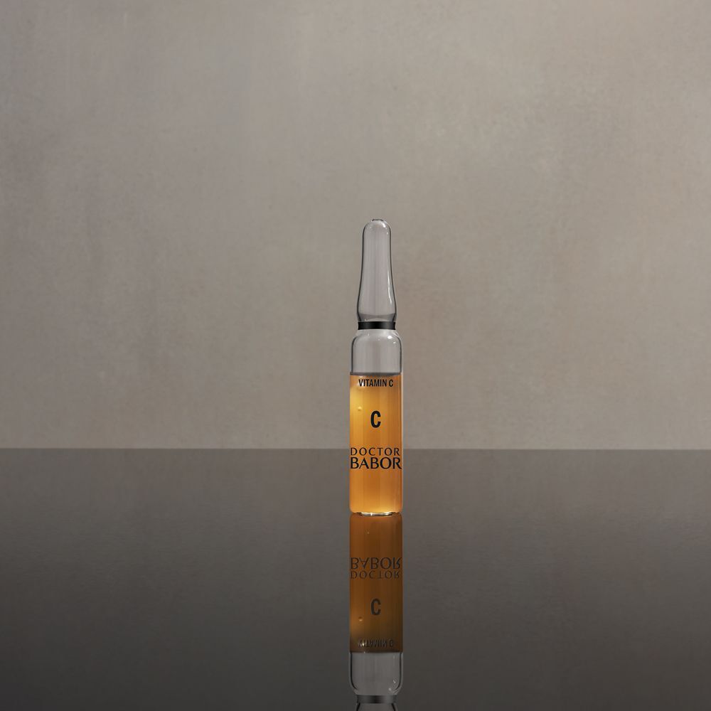 Glasampulle mit Serum. Aufschrift: C, Doctor BABOR. Reflektion auf glänzender Oberfläche.