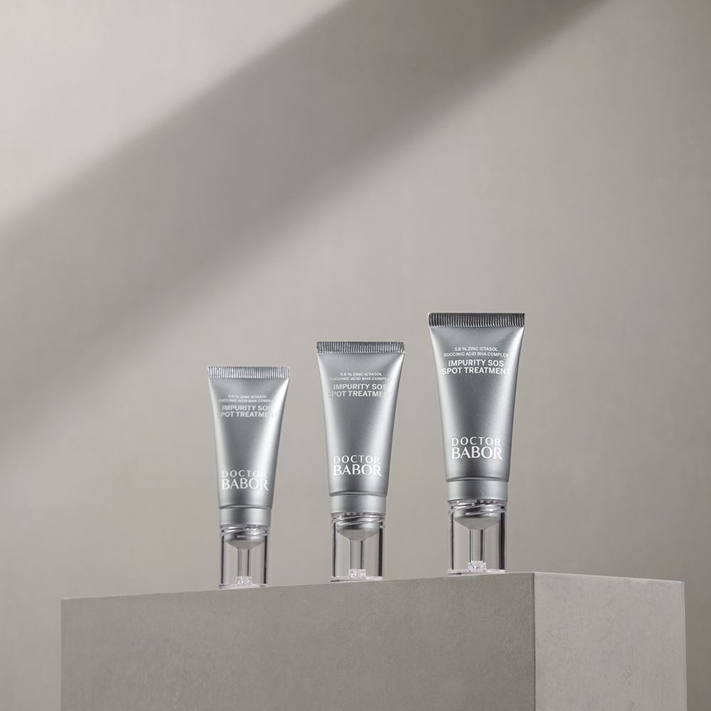Trois tubes argentés avec texte blanc. Nom du produit: IMPURITY SOS SPOT TREATMENT. Marque: DOCTOR BABOR. Sur surface grise.