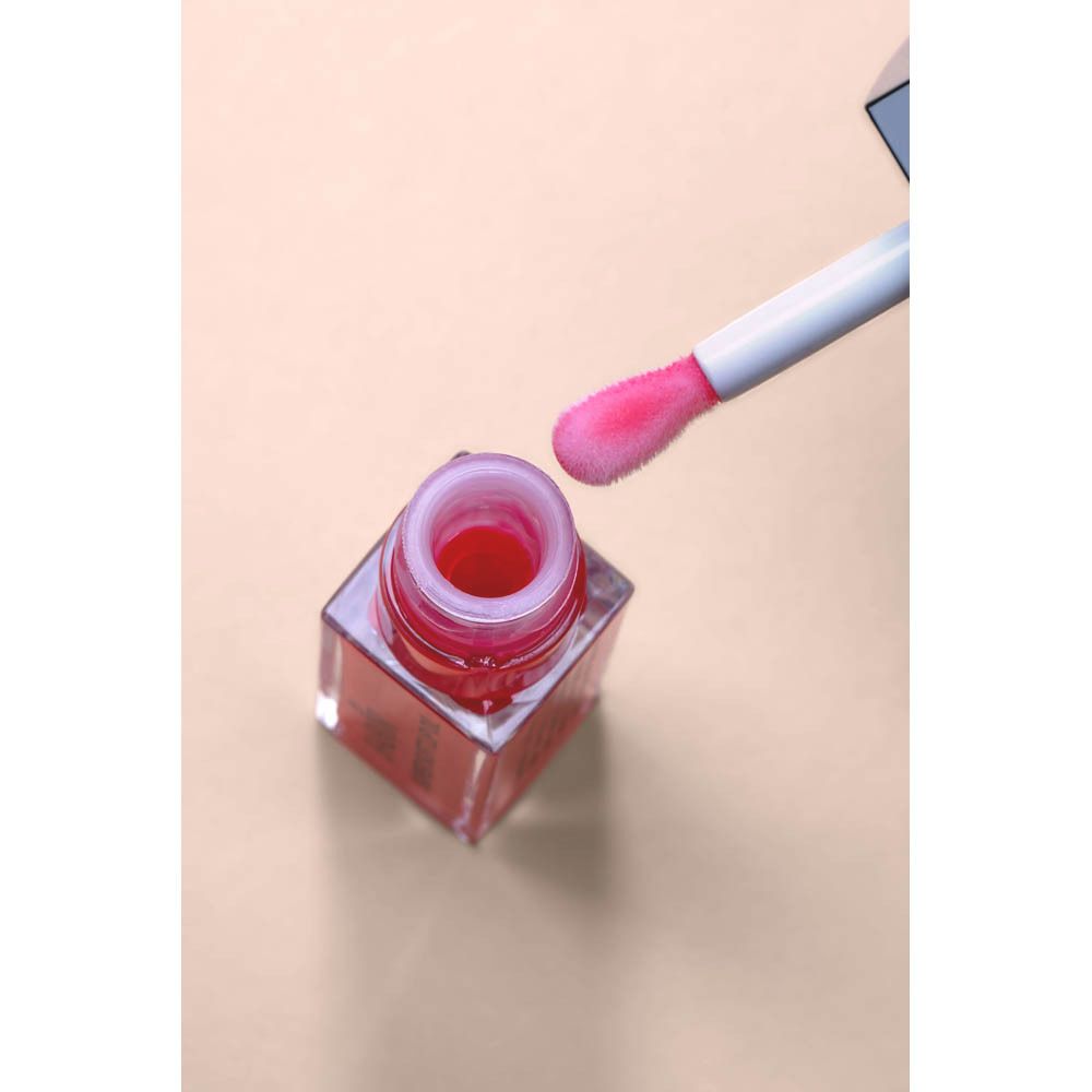 Offenes Lip Oil-Fläschchen mit Applikator. Rosa Inhalt. Rosa Applikatorbürste.