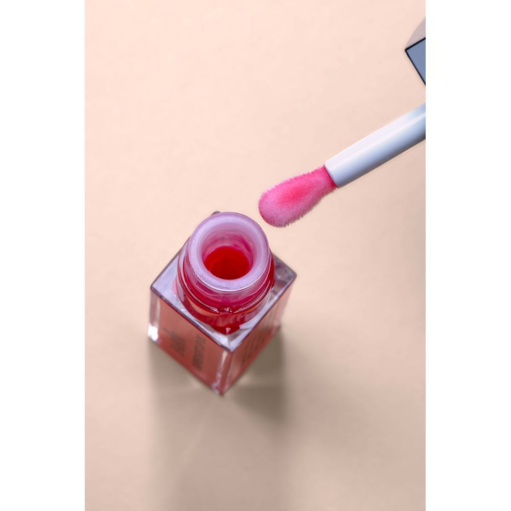 Geöffnete Lippenöl-Flasche mit Applikator. Rosa Öl im Fläschchen. Applikator mit rosa Spitze.