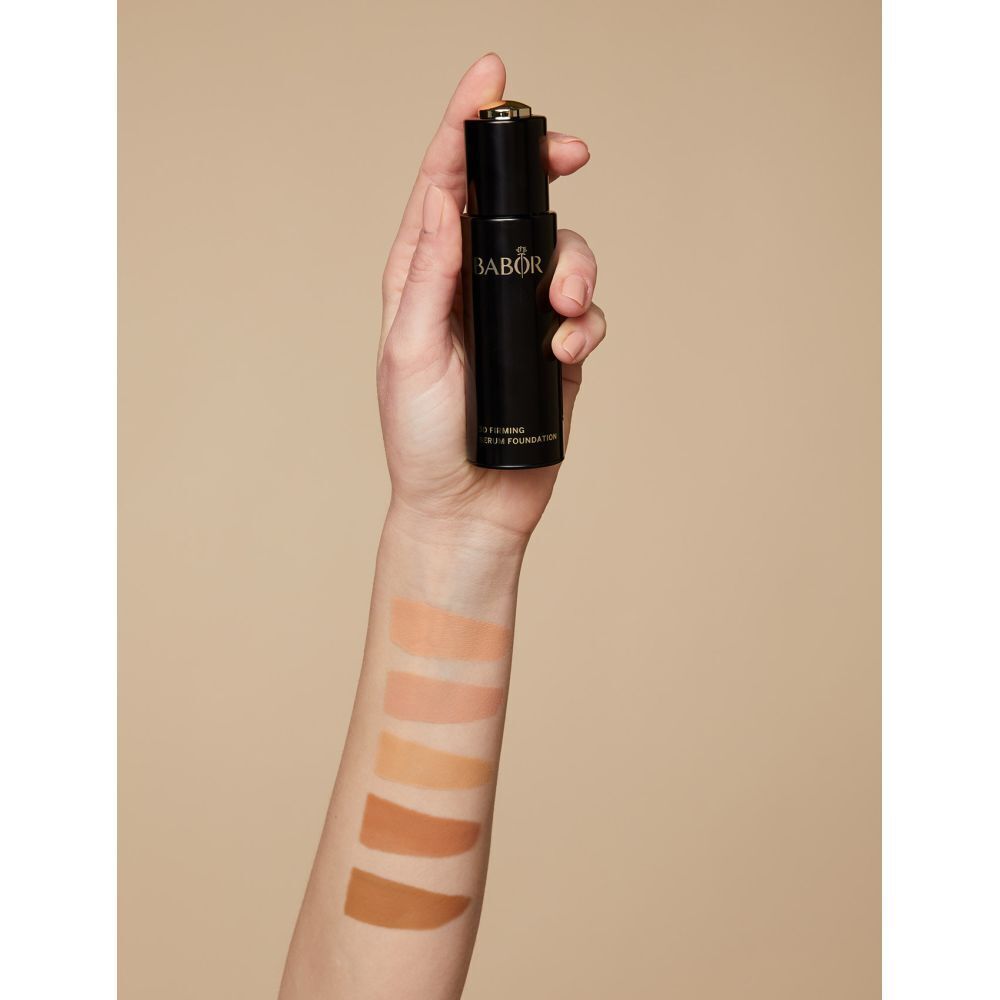 Hand hält Flasche. Auf Arm sind Farbmuster aufgetragen. Aufschrift BABOR und 3D Firming Serum Foundation.