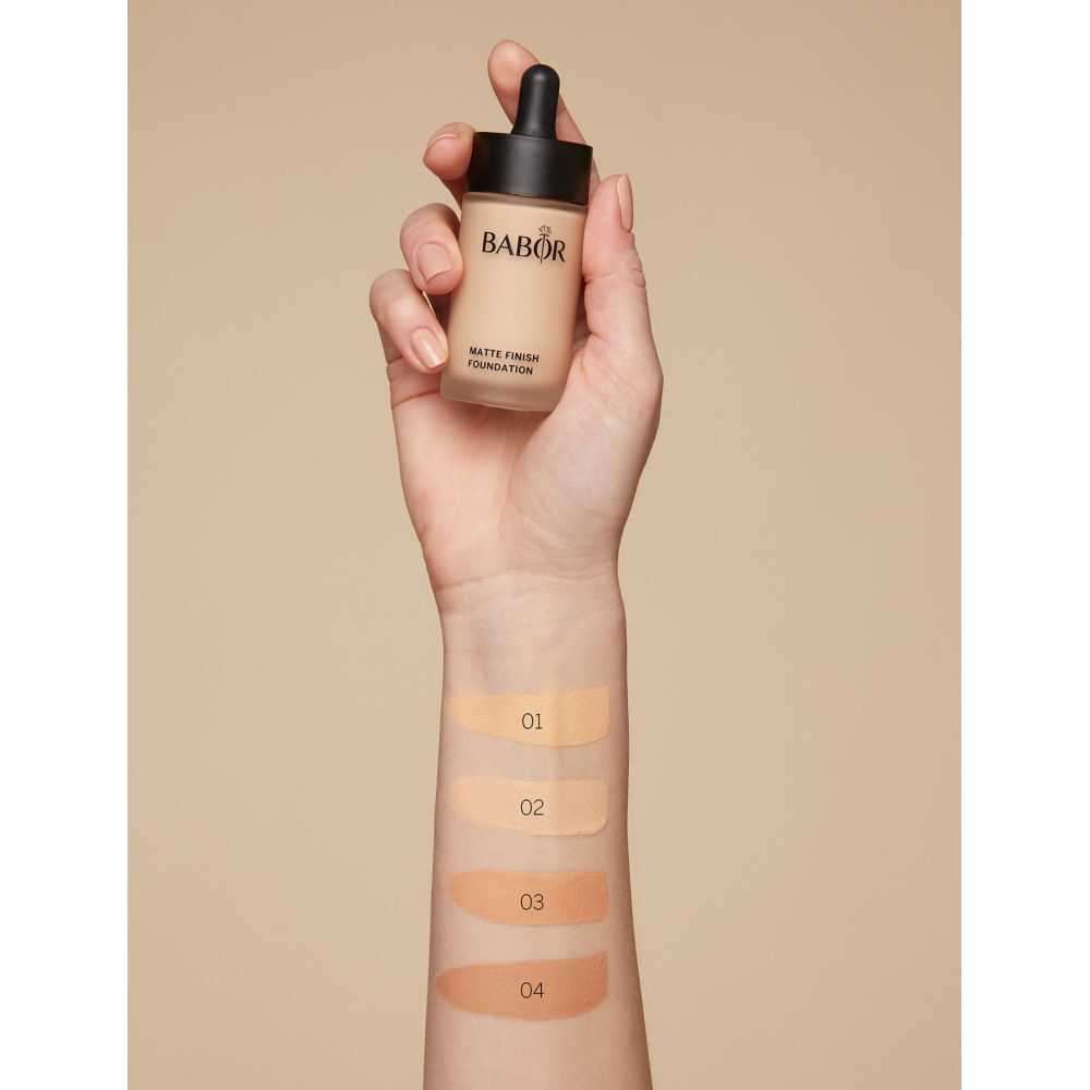Hand hält Foundation-Flakon. Arm mit Farbmustern: 01, 02, 03, 04.