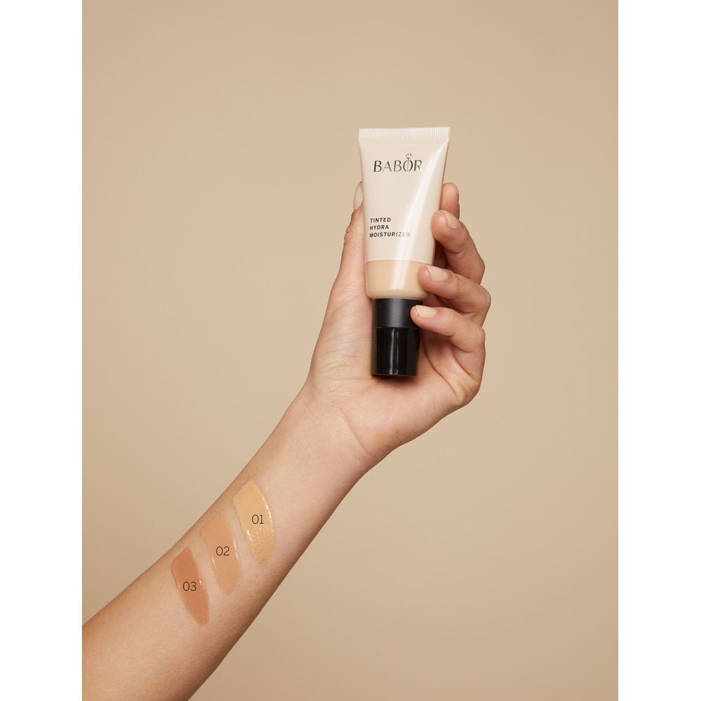 Hand mit BABOR Tinted Hydra Moisturizer und Farbmuster. Produkt und Farbtöne 01, 02, 03 sind sichtbar.