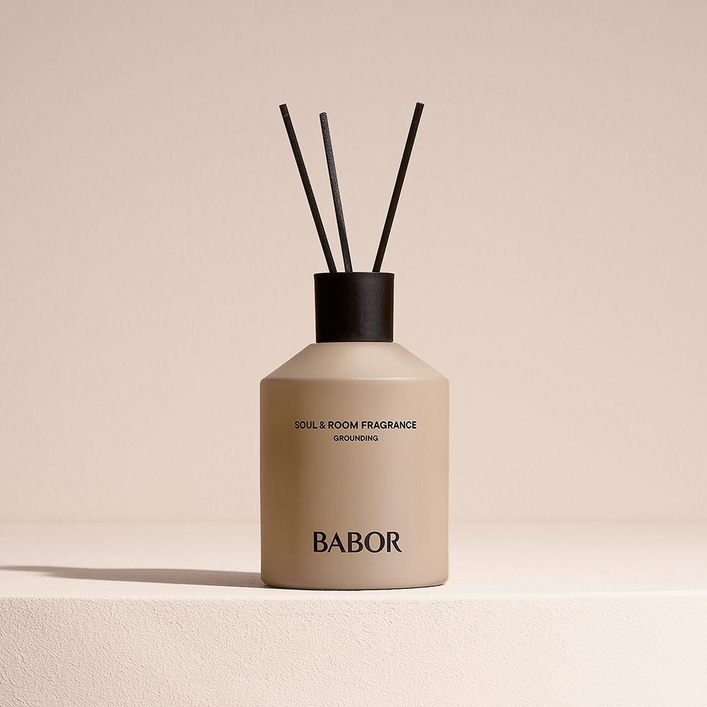 Flacon de parfum d'ambiance beige avec bâtonnets noirs. Inscription : Soul & Room Fragrance, Grounding, BABOR.
