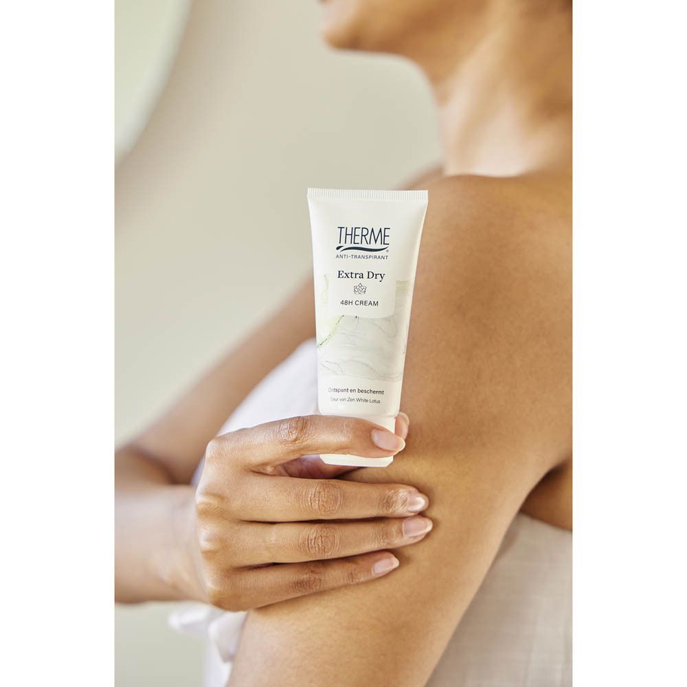 Persoon houdt Therme Anti-Transpirant Extra Dry Cream 48H vast. Product in de hand, arm in de buurt.