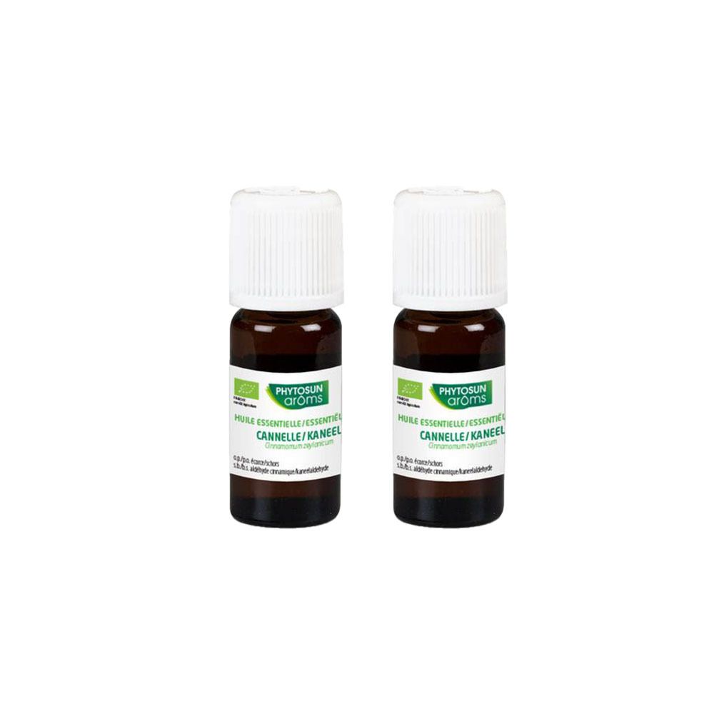Deux petites bouteilles marron avec bouchons blancs. Étiquettes avec nom et logo du produit. Texte: Huile essentielle Cannelle.