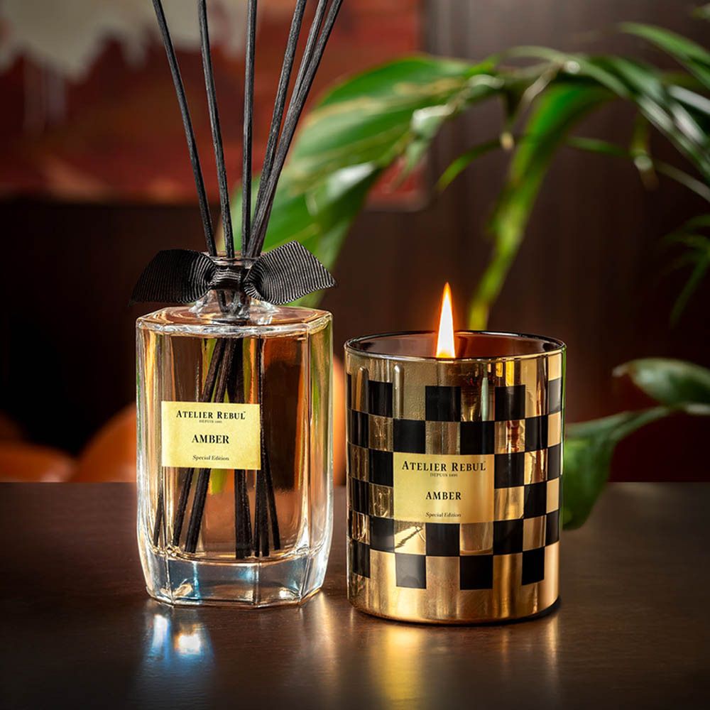 Diffuseur de parfum et bougie dans un verre à carreaux or et noir. Inscription : "AMBER". Ruban noir sur le diffuseur.