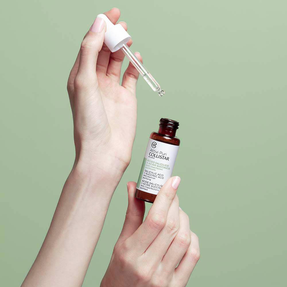 Handen houden fles met pipet. Product op groene achtergrond.