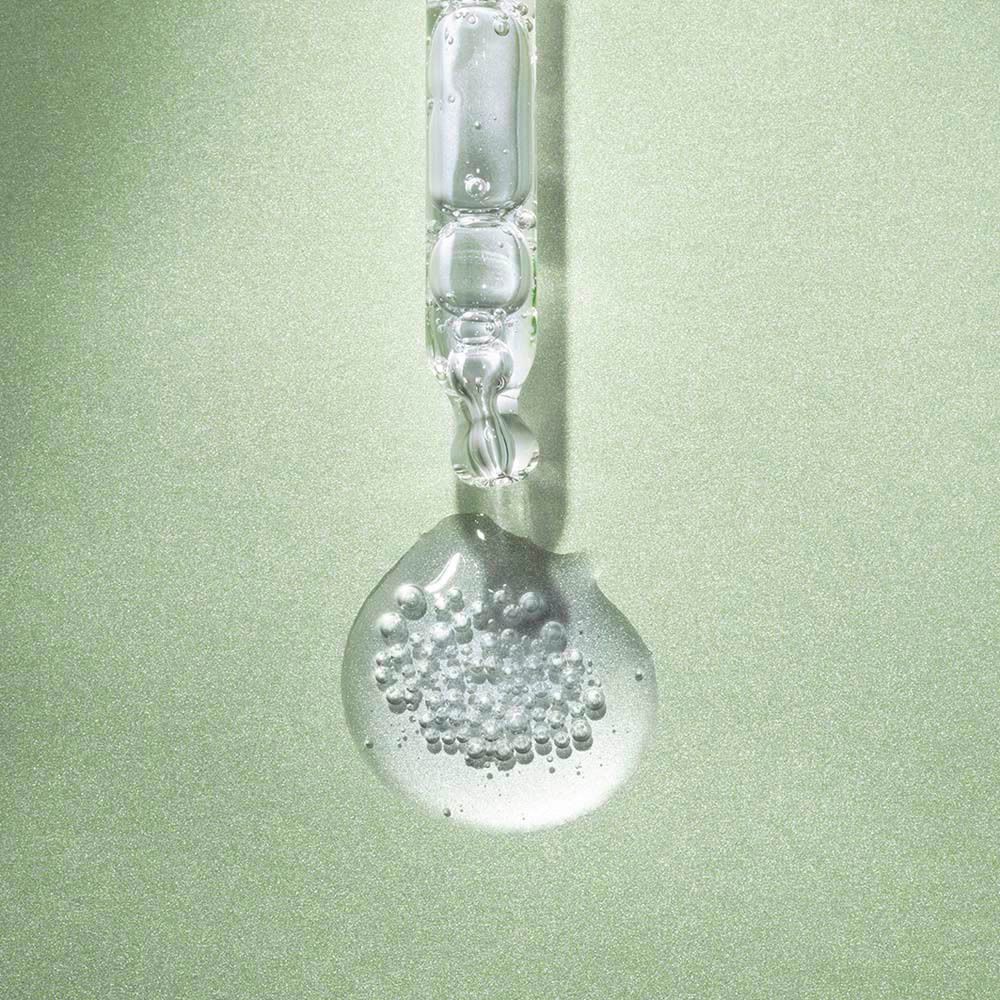 Pipet met product op groene achtergrond. Product in druppelvorm.