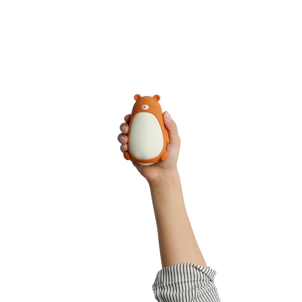 Moonbird Moonbuddy Barry l'ours, orange et blanc, tenu dans une main. Vue de dessus.